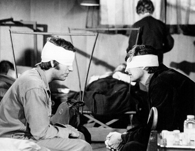 Two blindfolded men looking towards but not seeing each other.